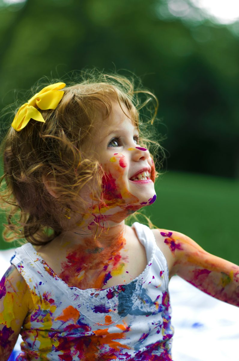 Child covered in colourful paint smiling